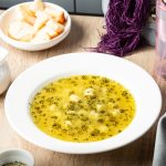 a plate of azerbaijani dushbara dumpling soup garnished with dried mint leaves